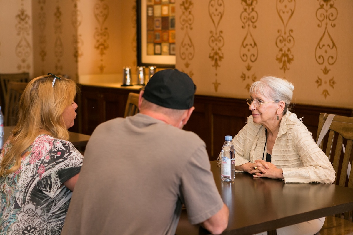 Three people have a conversation in a restaurant